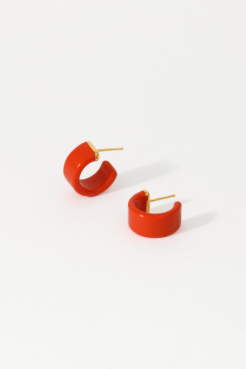 A pair of tangerine huggie earrings with 18K gold plated sterling silver studs on a white background.